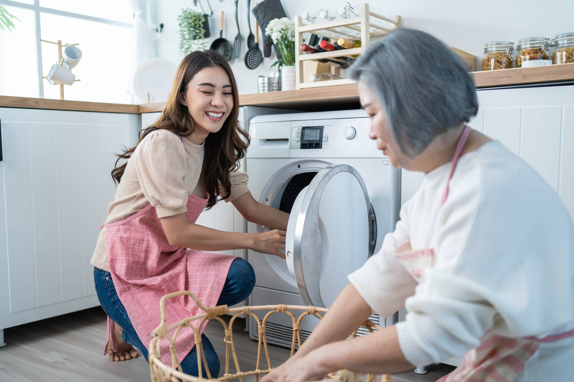 A younger woman helping a senior woman with laundry.