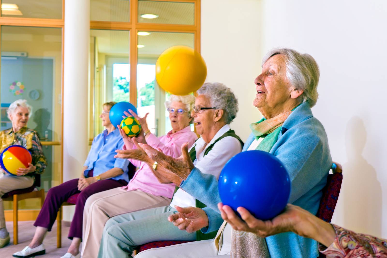 Senior women with dementia all holding a ball.