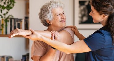 Senior woman stretching with a caregiver.