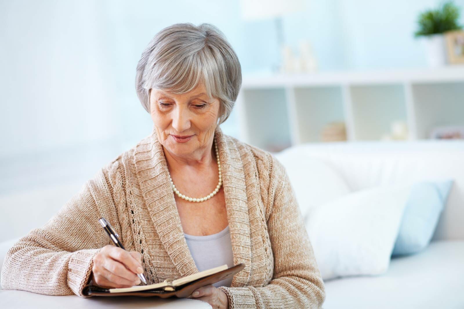 Senior woman with dementia writing in a notebook.