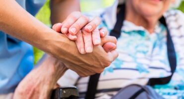 A caregiver holding the hand of an elderly woman