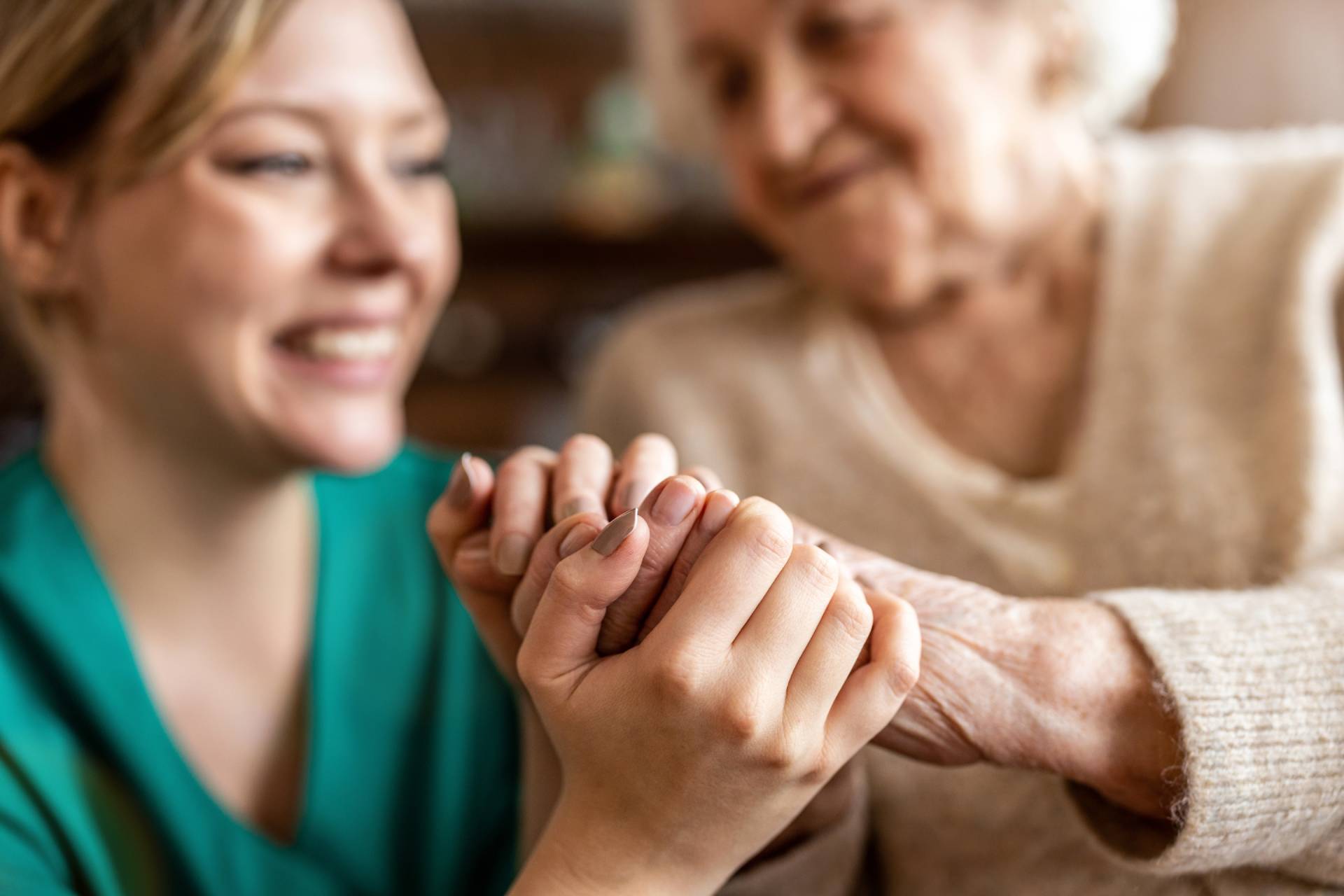 A caregiver holding hands with a senior woman.