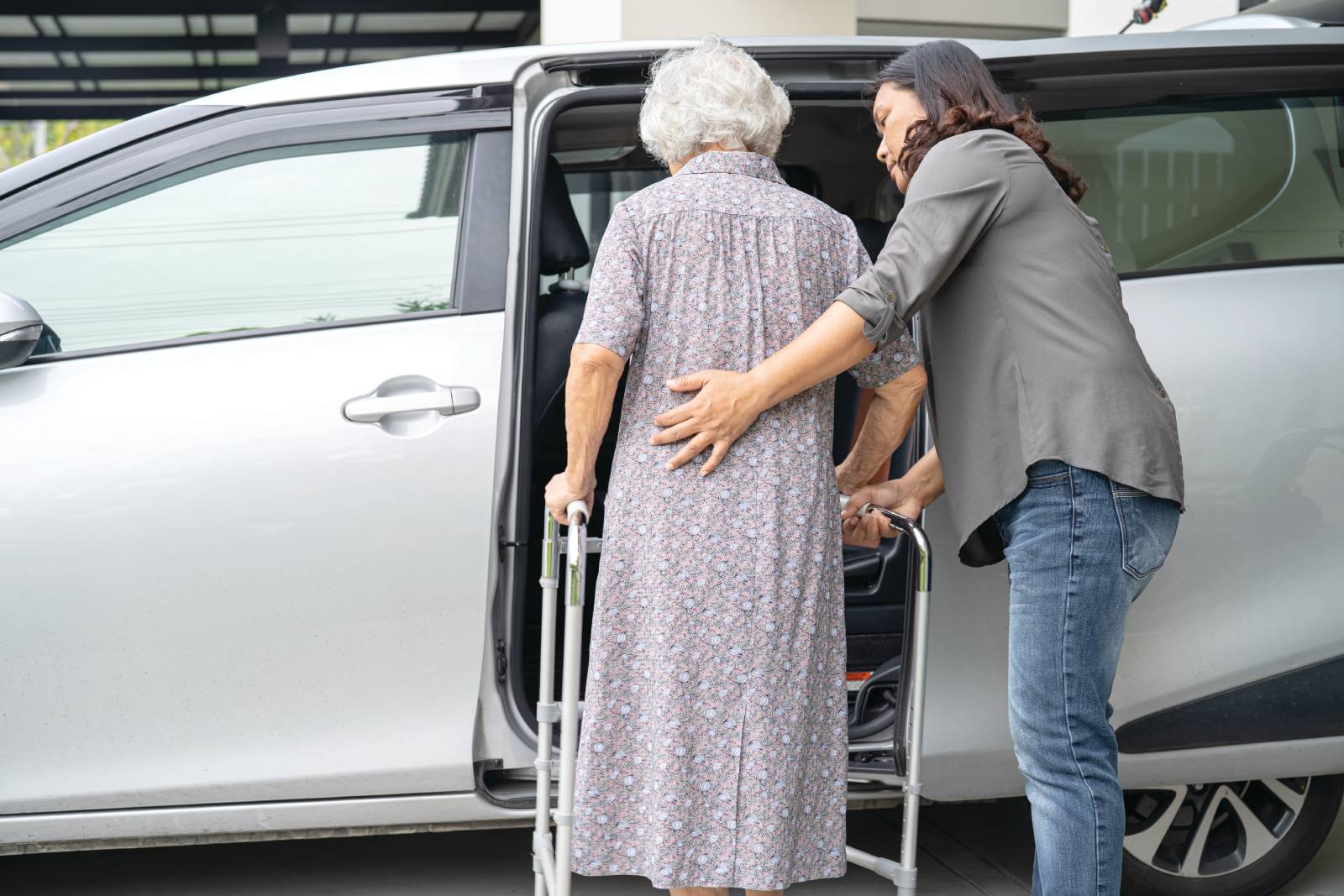 A caregiver helping a senior get into a van.