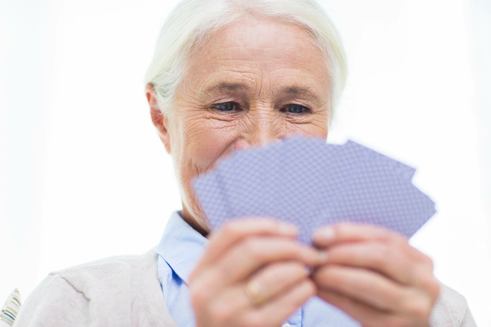 Senior woman looking at a deck of cards in her hand.