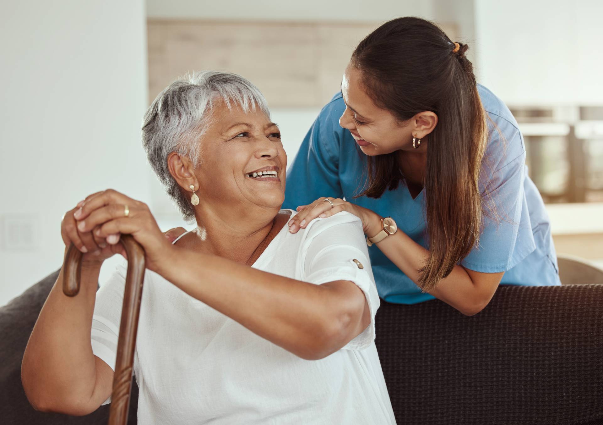 A senior sitting and smiling at a female caregiver.