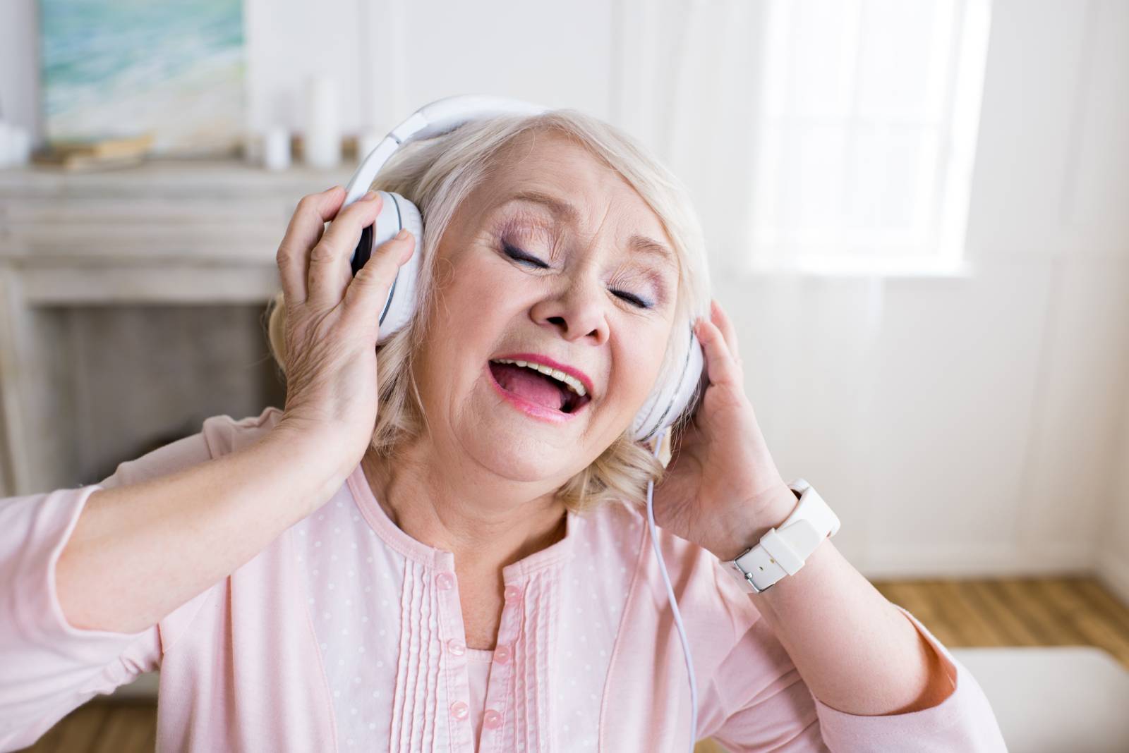 Woman with dementia listening to music through headphones and singing.