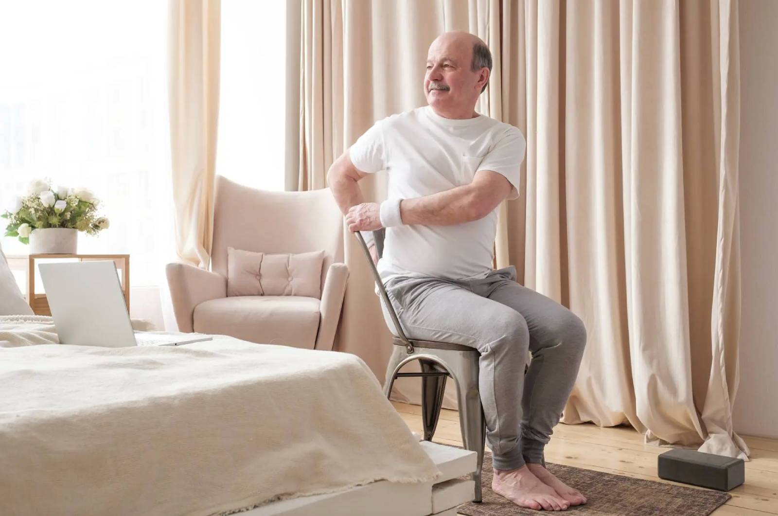 Senior man with dementia doing yoga on a chair.