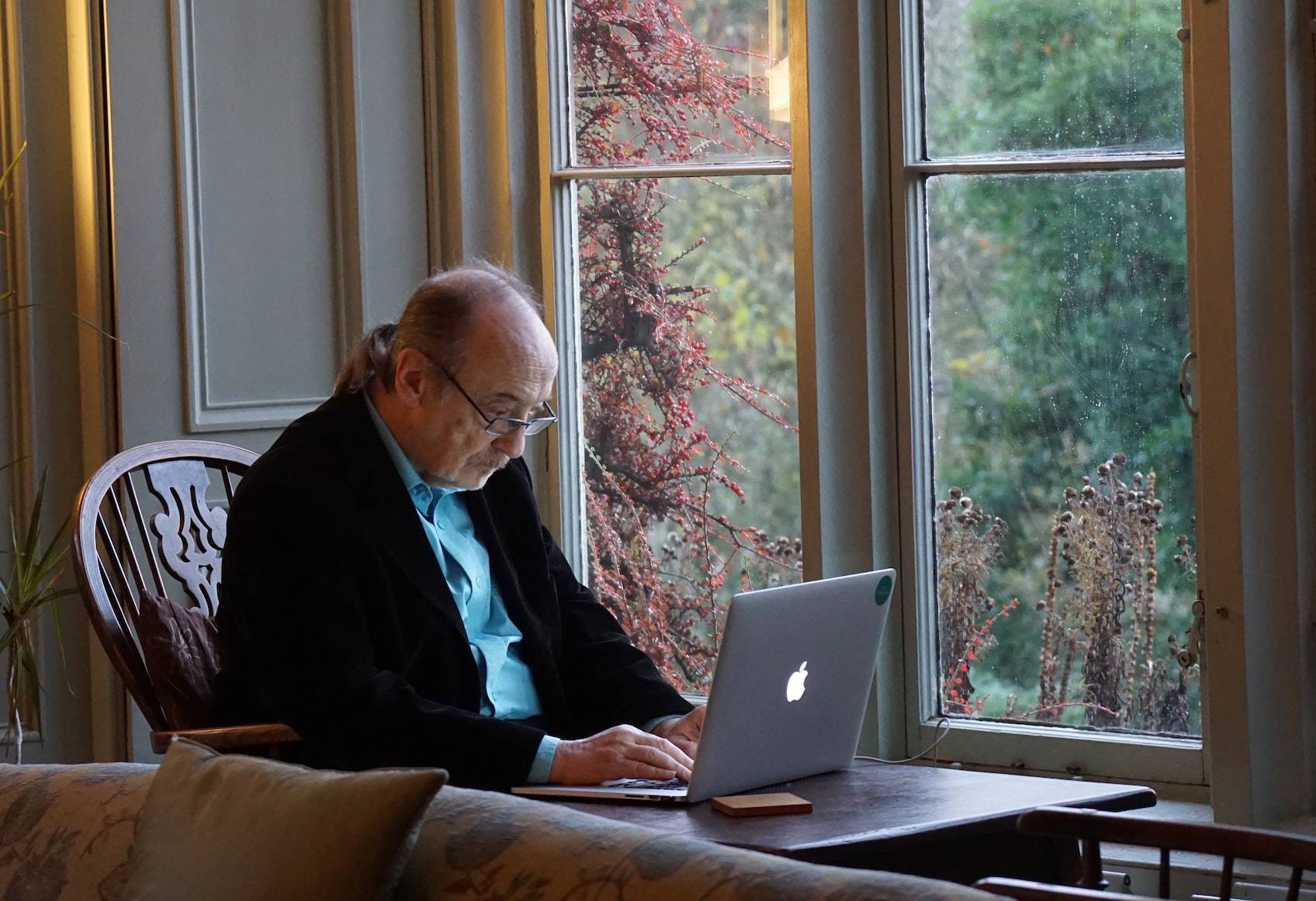 Senior man playing computer games on an Apple laptop.
