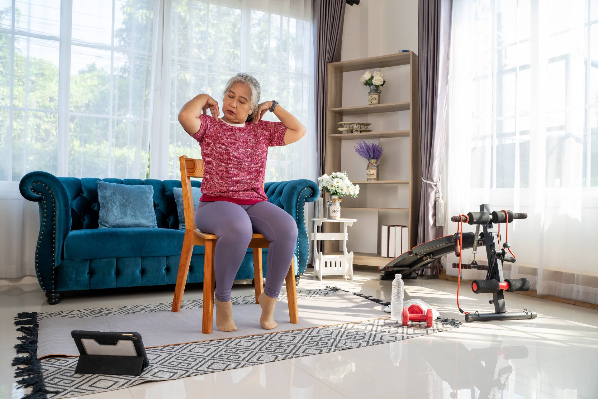 Senior woman doing shoulder rolls in her living room.